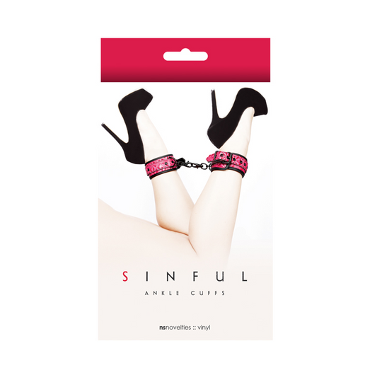 The image shows a pair of pink ankle cuffs with faux leather design, packaged on a red and white card with the brand name 'NS Novelties' and the product name 'Sinful Ankle Cuffs'.