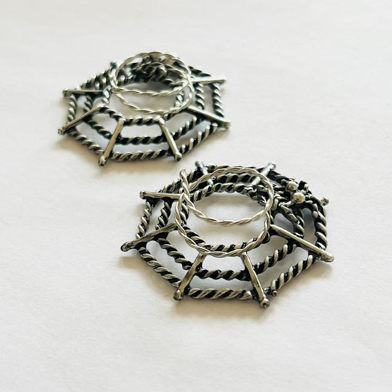 Close-up angled view of twisted metal spider web nipple rings