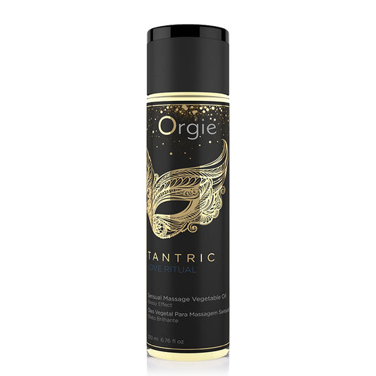 A black cylindrical container with gold accents, labeled 'Orgie Tantric Love Ritual' with an image of a golden mask on the front, indicating it is a massage oil product.