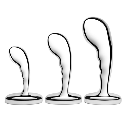 Three stainless steel anal plugs from the b-Vibe P-Spot Training Set in small, medium, and large sizes displayed against a reflective background.