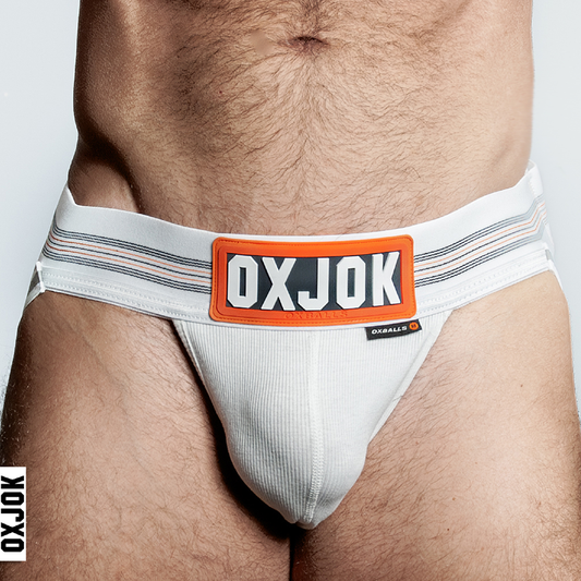 A white jockstrap with an orange and white striped elastic waistband labeled 'OXJOK' and a rubber OXJOK logo on the front. The product is modeled from a rear and partial side view, highlighting the pouch and waistband.