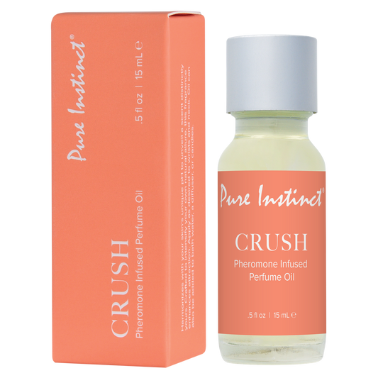 The image shows a Pure Instinct perfume oil bottle with a white cap, next to its orange packaging box. The label on the bottle reads 'CRUSH Pheromone Infused Perfume Oil'.