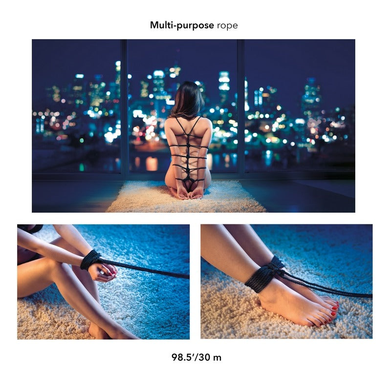 Person sitting on a rooftop at night with city lights, wearing a black multi-purpose rope.